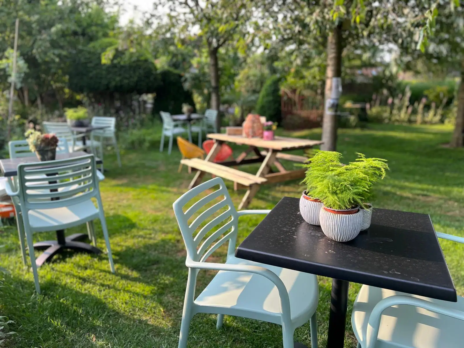 Gezellige zitplek in de tuin van Bar Botanique in Nevele-Deinze – zomerbar met tafels tussen het groen